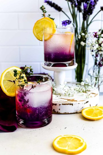 Two Lavender Haze Mocktails decorated with thyme and lemon slices.