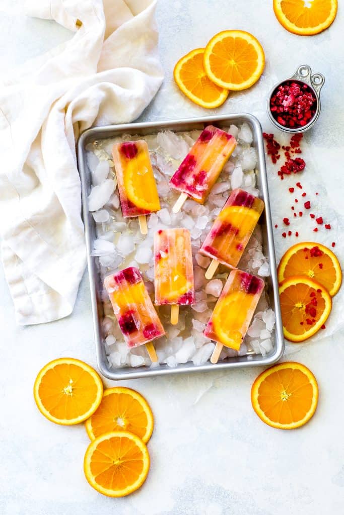 Sangria popsicles on a baking sheet full of ice.