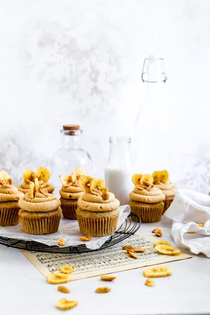 Peanut butter banana cupcakes on a cooling racks and jugs of milk.