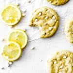 Vegan lemon white chocolate cookie with a bite taken out of it and lemon slices.