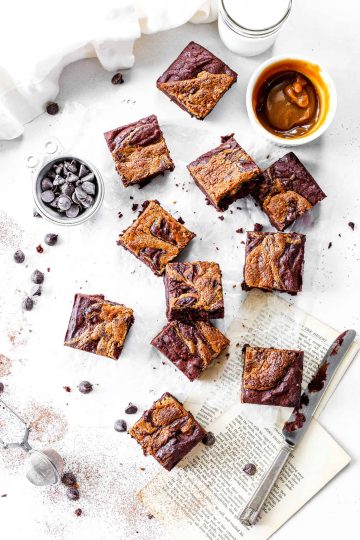 Sliced vegan peanut butter brownies, cup of milk and scattered chocolate chips.