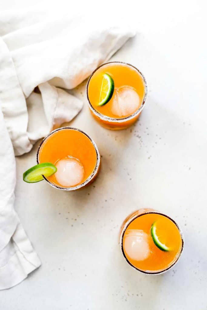 Overhead view of three Taylor Swift "sweet nothing" mocktails garnished with lime slices and a linen napkin.