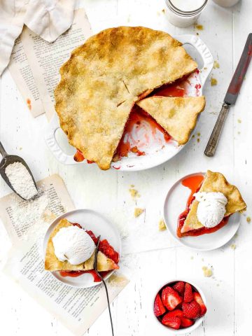 Strawberry rhubarb pie missing a couple slices and two slices on white plates topped with ice cream.