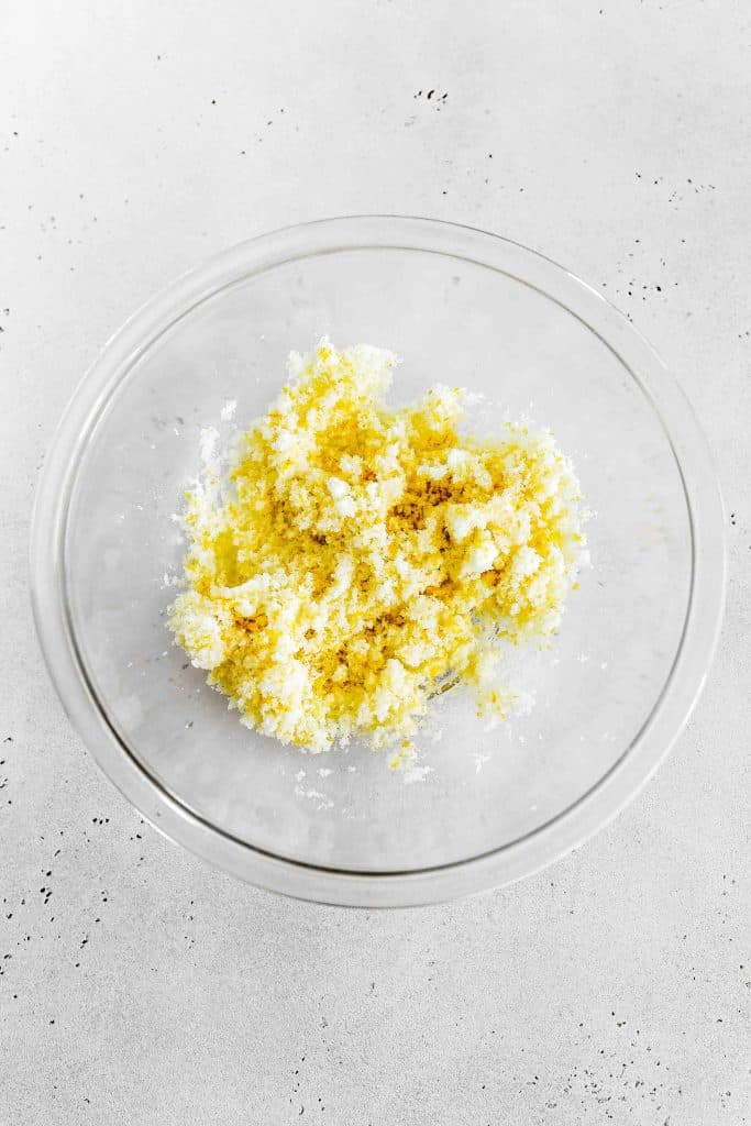 Sugar and lemon zest combined in a glass bowl.