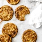 Vegan snickerdoodles, one with a bite taken out of it, and a linen napkin.