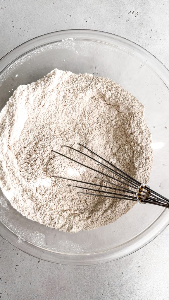 Glass bowl filled with the dry ingredients necessary for making pumpkin pie cupcakes.