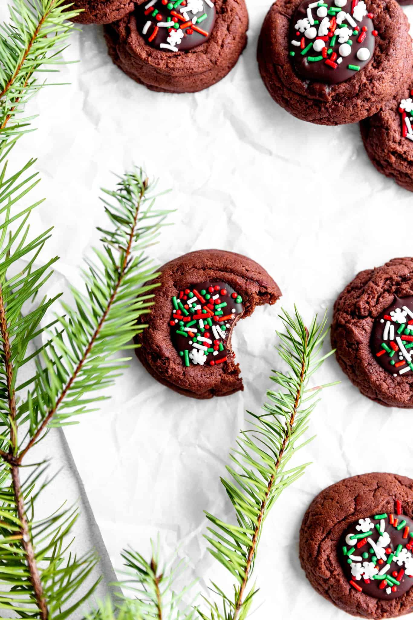 Vegan chocolate thumbprint cookie with a bite taken out of it surrounded by more cookies.