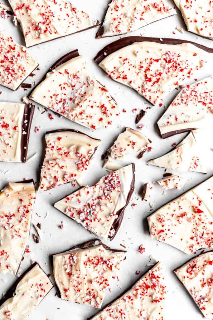 Pieces of vegan peppermint bark spread out on a white surface.