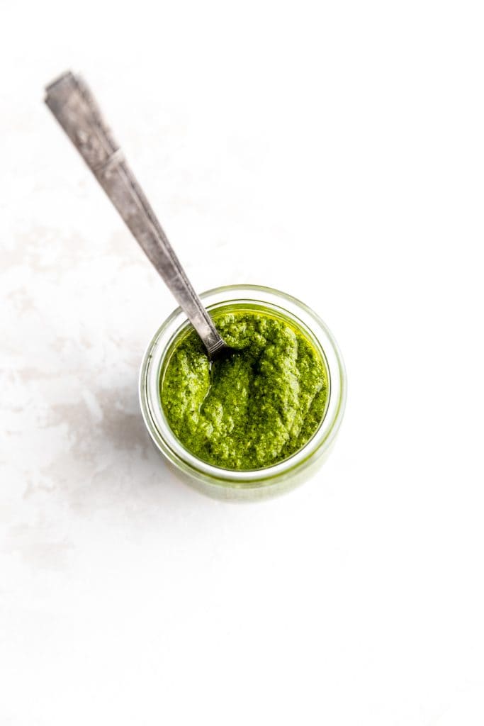 Glass jar filled with pesto sauce.