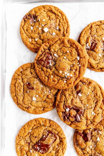 Vegan espresso chocolate chip cookies layered on a sheet of parchment paper.