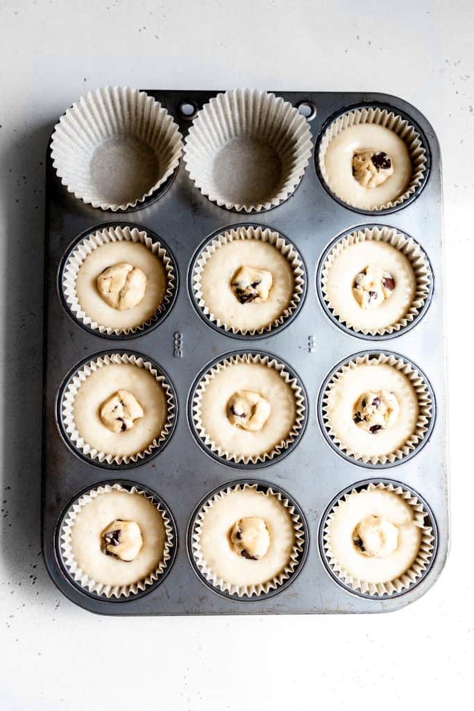 Unbaked cupcakes in a cupcake pan with cookie dough pressed into the center of each.