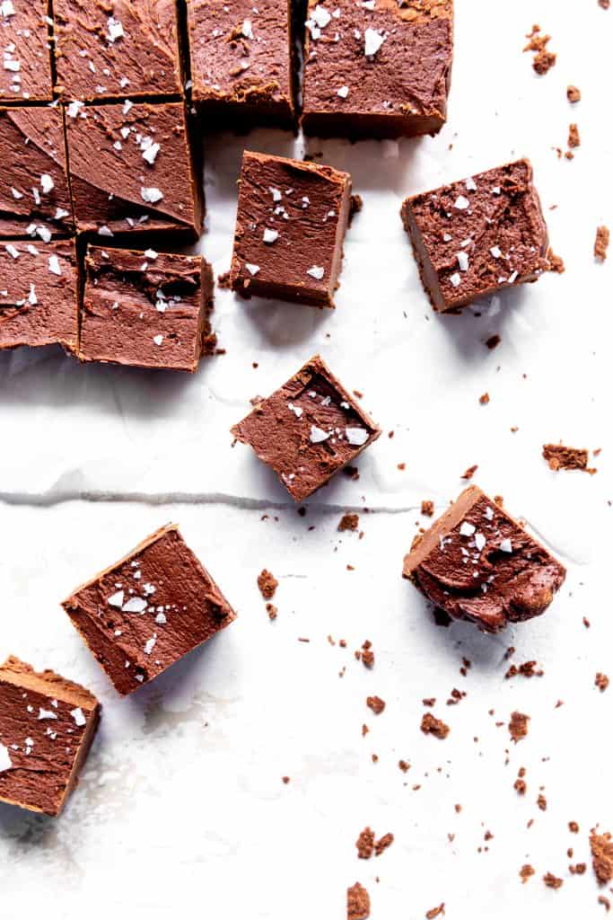 Sliced vegan fudge sprinkled with sea salt spread across a white surface.