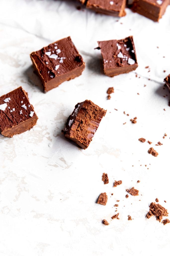 Piece of vegan fudge on a white surface with a bite taken out of it.