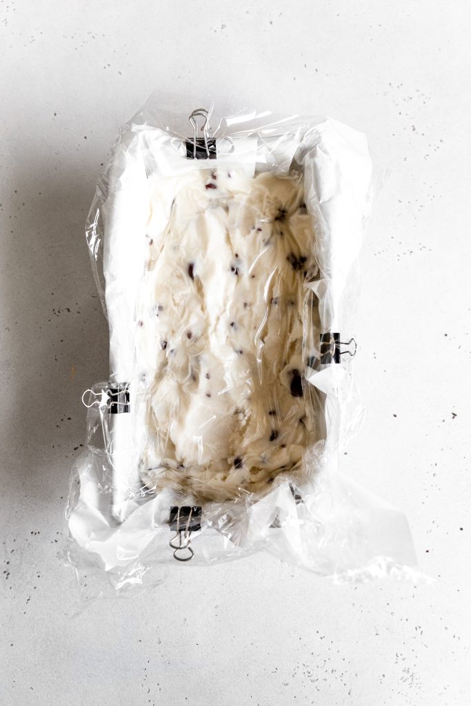 Frozen mint chip ice cream in a loaf pan covered tightly with plastic wrap.