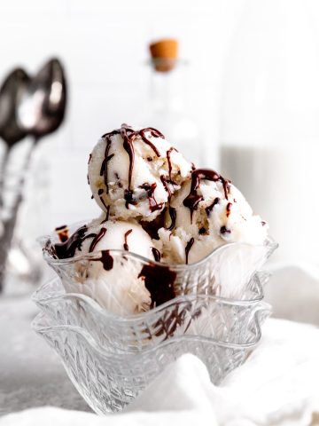 Glass bowl filled with vegan mint chip ice cream stacked on more glass bowls.