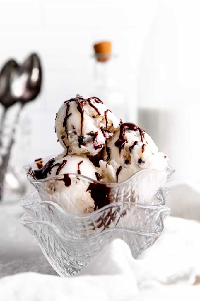 Glass bowl filled with vegan mint chip ice cream stacked on more glass bowls.