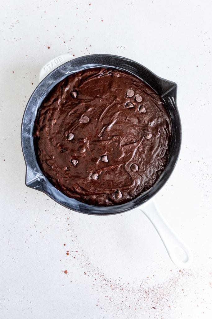 Cast iron skillet filled with unbaked vegan brownie batter.