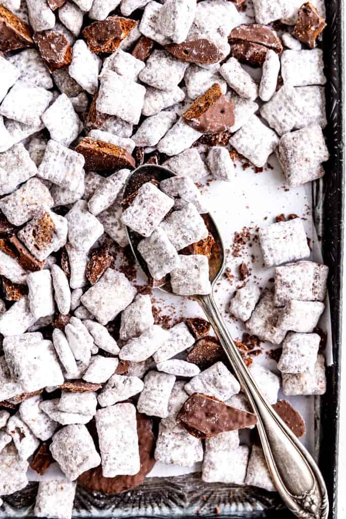 Silver spoon scooping up thin mint muddy buddies from a baking sheet.