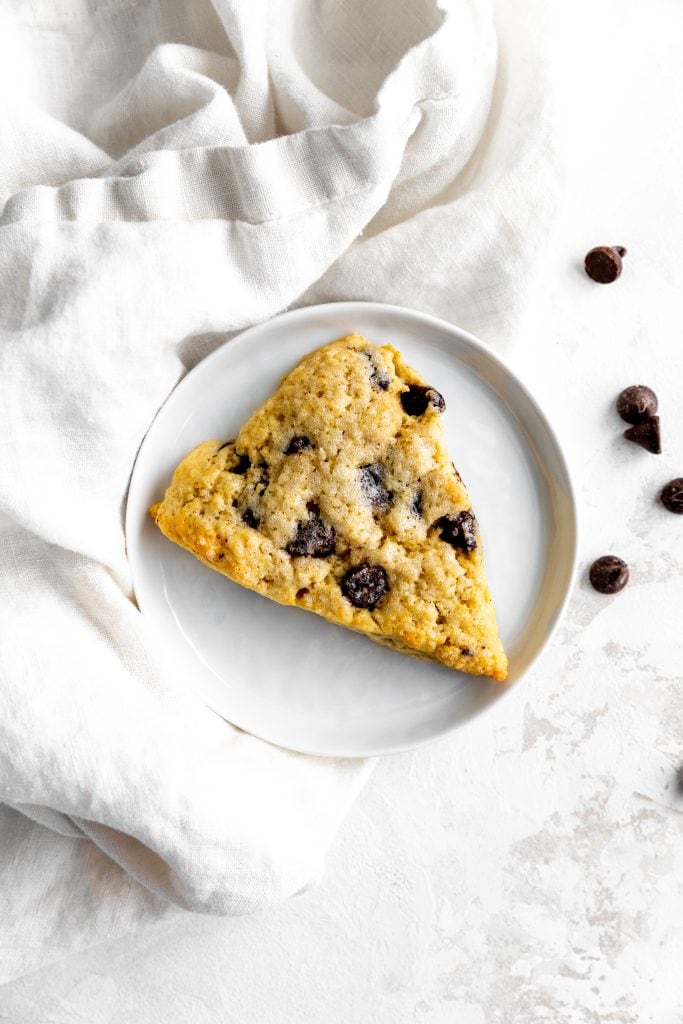 Chocolate chip scone on a white plate and a white linen napkin.