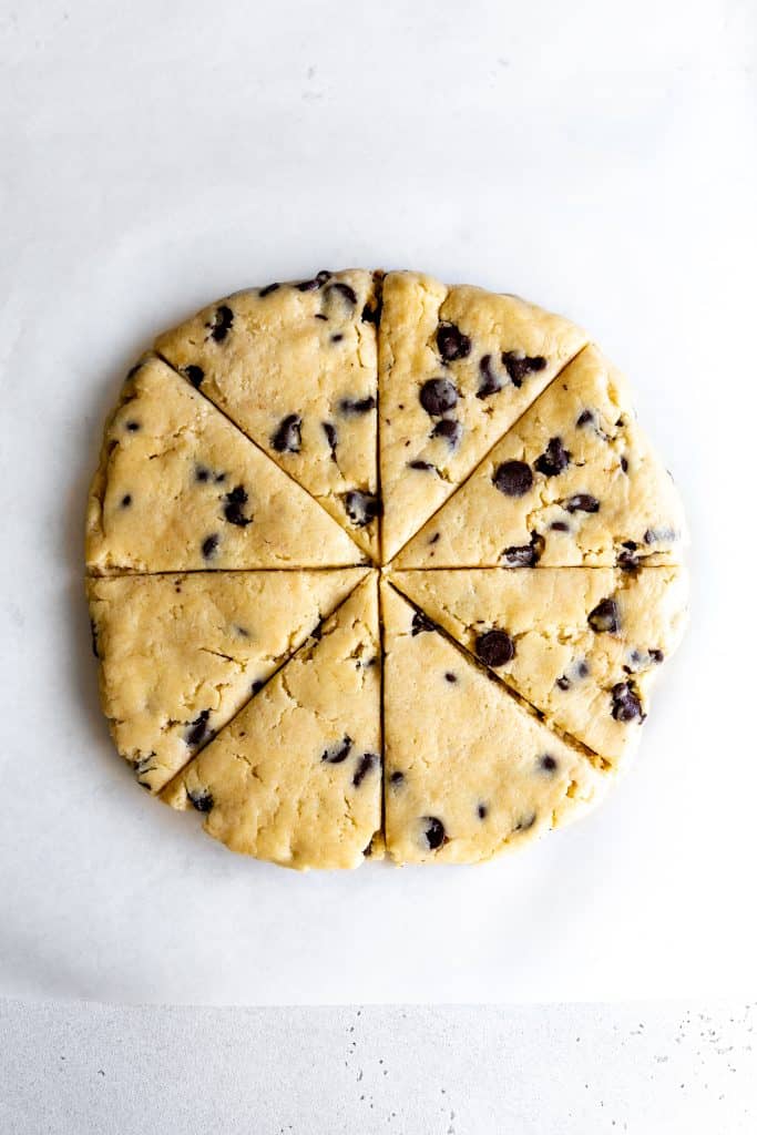 Cut and unbaked scones arranged in a circle on a sheet of parchment paper.