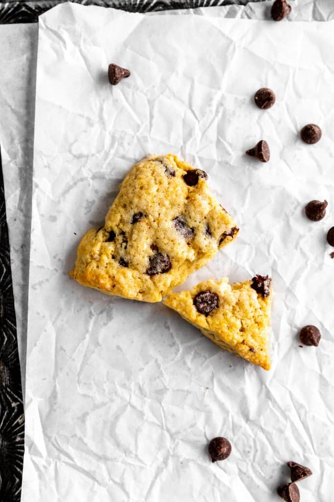 Vegan chocolate chip scone broken in half on baking sheet.