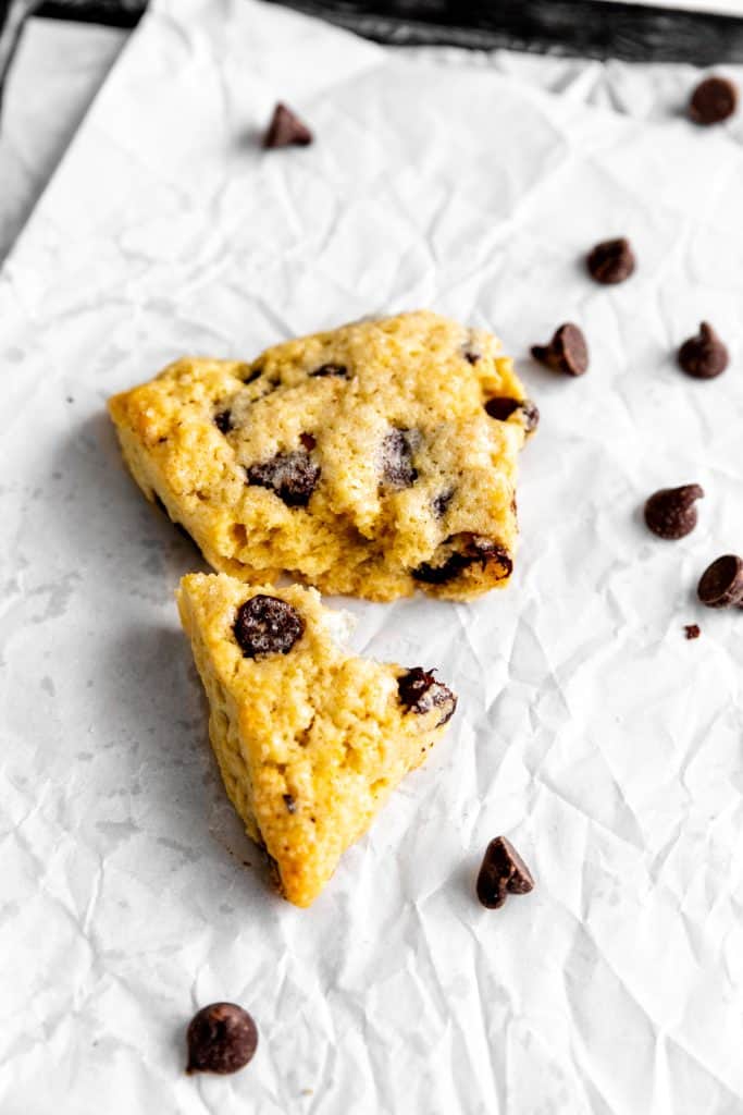 Chocolate chip scone broken in half on baking sheet.