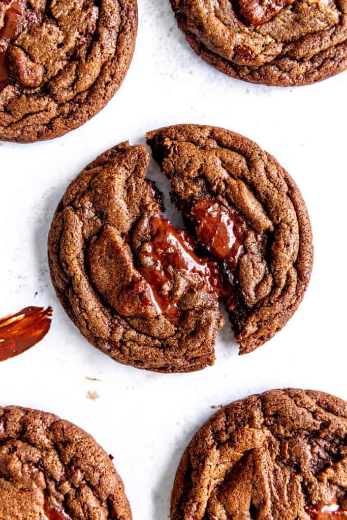 Vegan double chocolate cookie being pulled apart on a baking sheet.