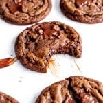 Double chocolate cookie with a bite taken out of it on a baking sheet.