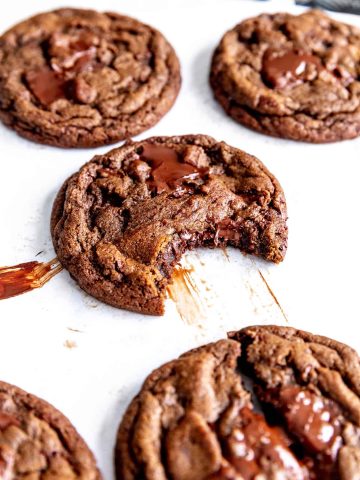 Double chocolate cookie with a bite taken out of it on a baking sheet.