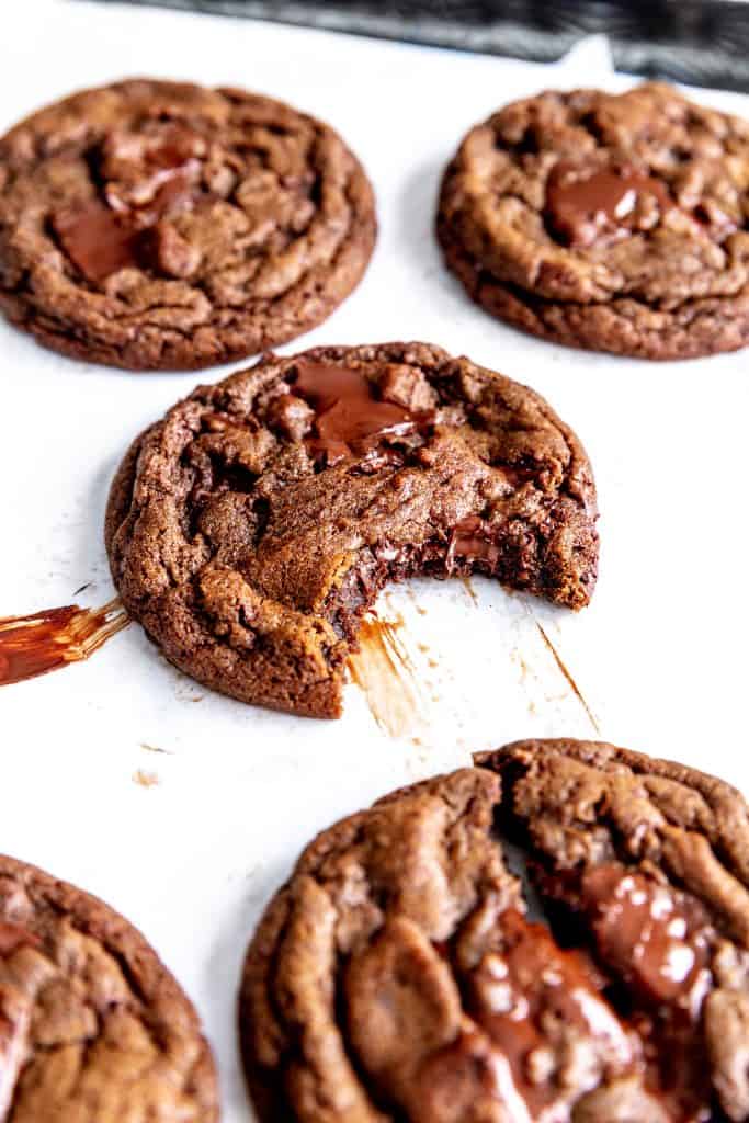 Double chocolate cookie with a bite taken out of it on a baking sheet.