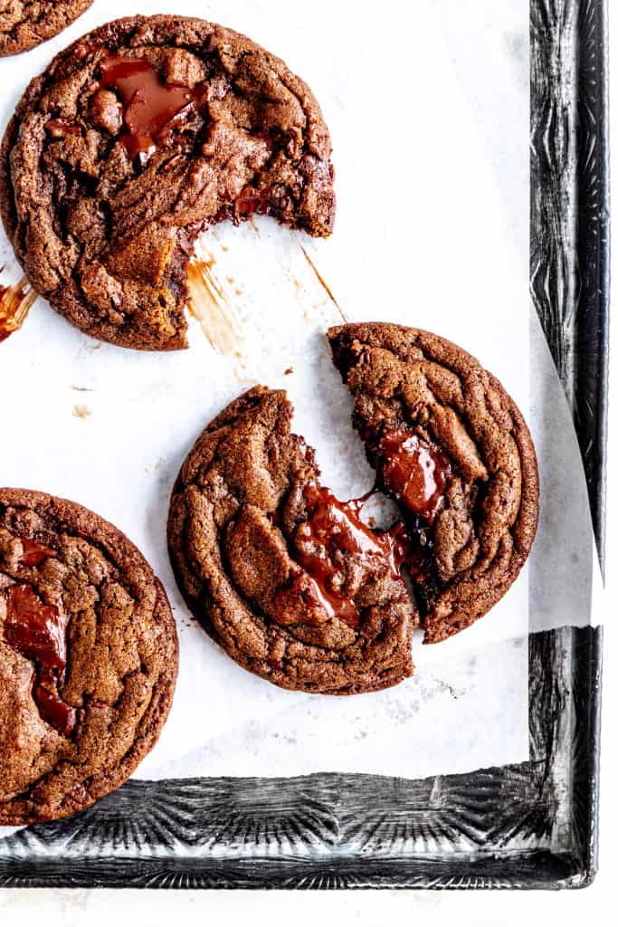 Double chocolate cookie broken in half on a baking sheet.