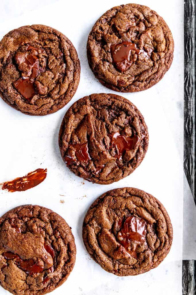 Double chocolate cookies on a baking sheet smeared with melted chocolate.