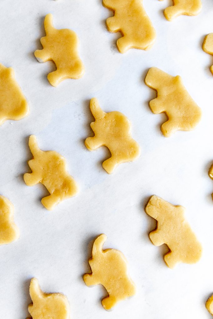 Unbaked, animal-shaped vegan sugar cookies on a baking sheet.