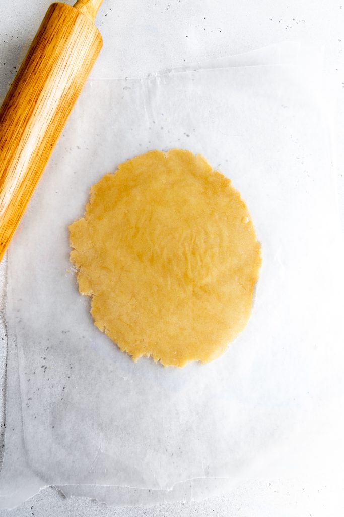 Rolled out sugar cookie dough and a rolling pin.