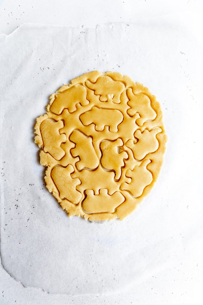 Rolled out sugar cookie dough with cut out animal shapes.