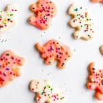 Pink and white animal cookies spread out on a white surface.