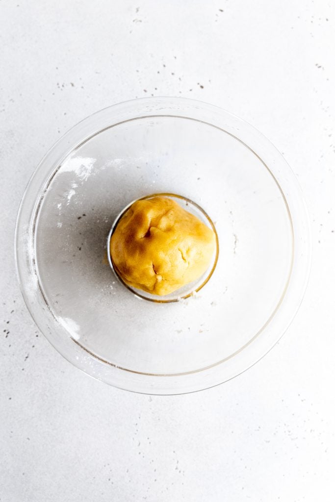 Ball of vegan sugar cookie dough in a glass bowl.