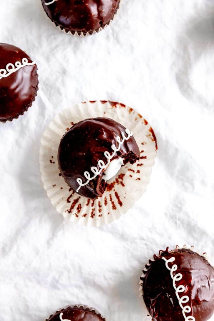 Vegan hostess cupcake with a bite taken out of it sitting on a cupcake wrapper.