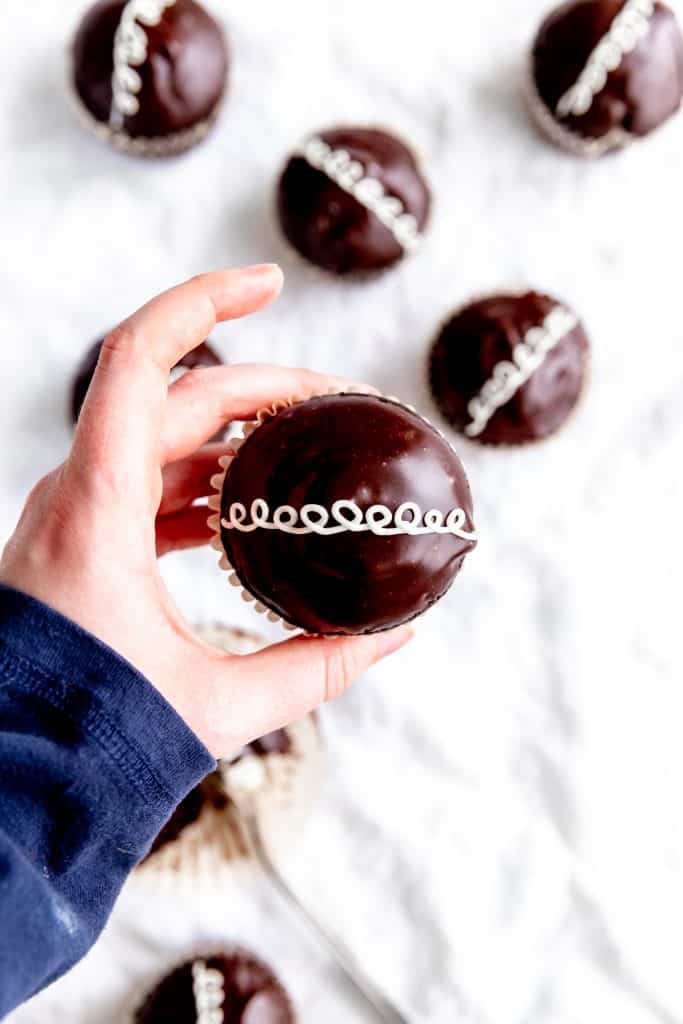 Hand holding a vegan hostess cupcake.