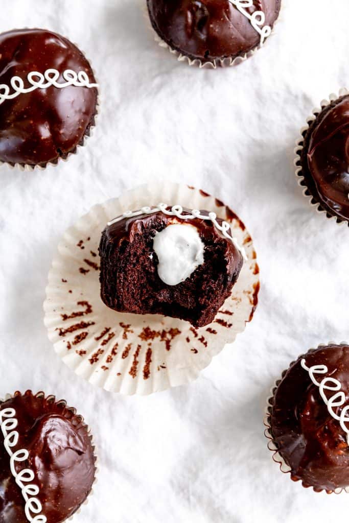 Vegan hostess cupcake with a bite taken out of it lying on its side.