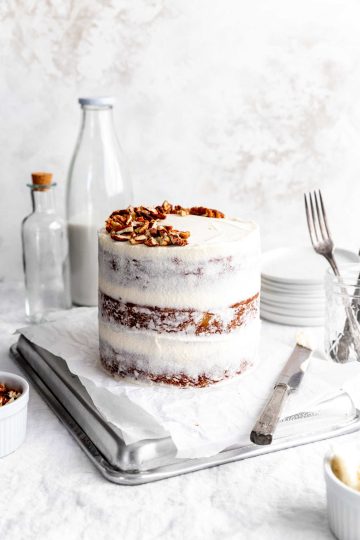 Hummingbird cake on a baking sheet, a jug of milk and a cup of pecans.