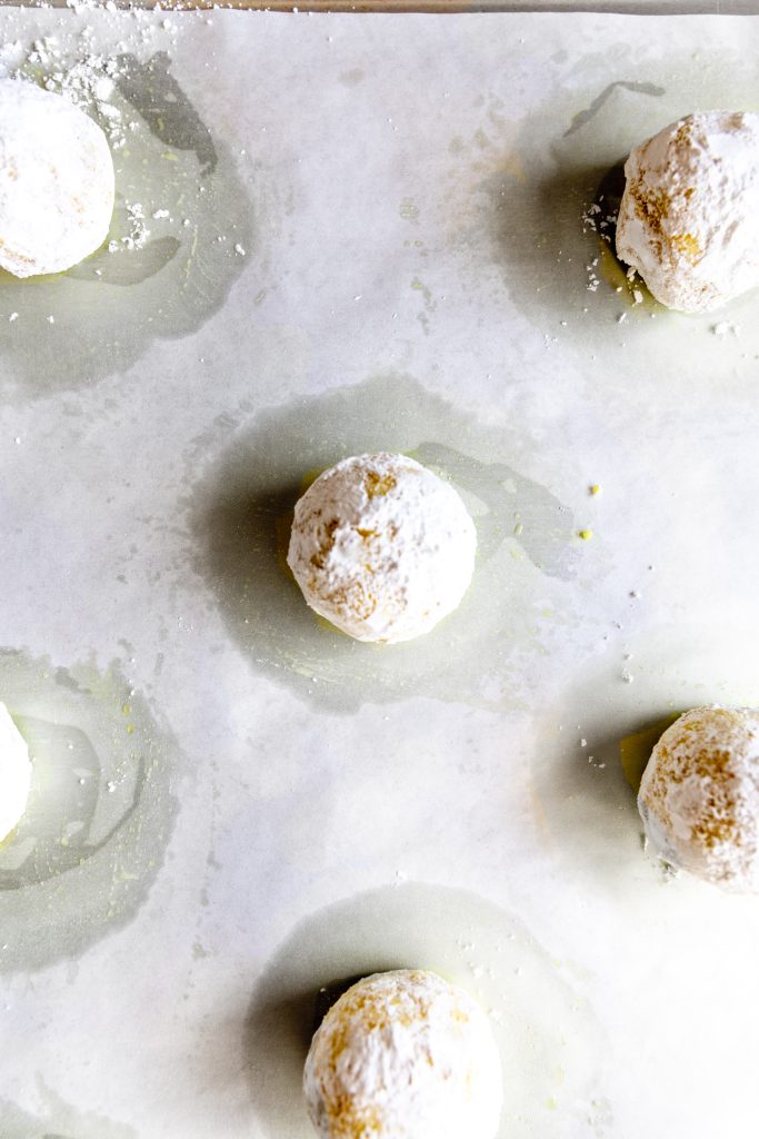 Unbaked lemon crinkle cookies on a baking sheet lined with parchment paper.