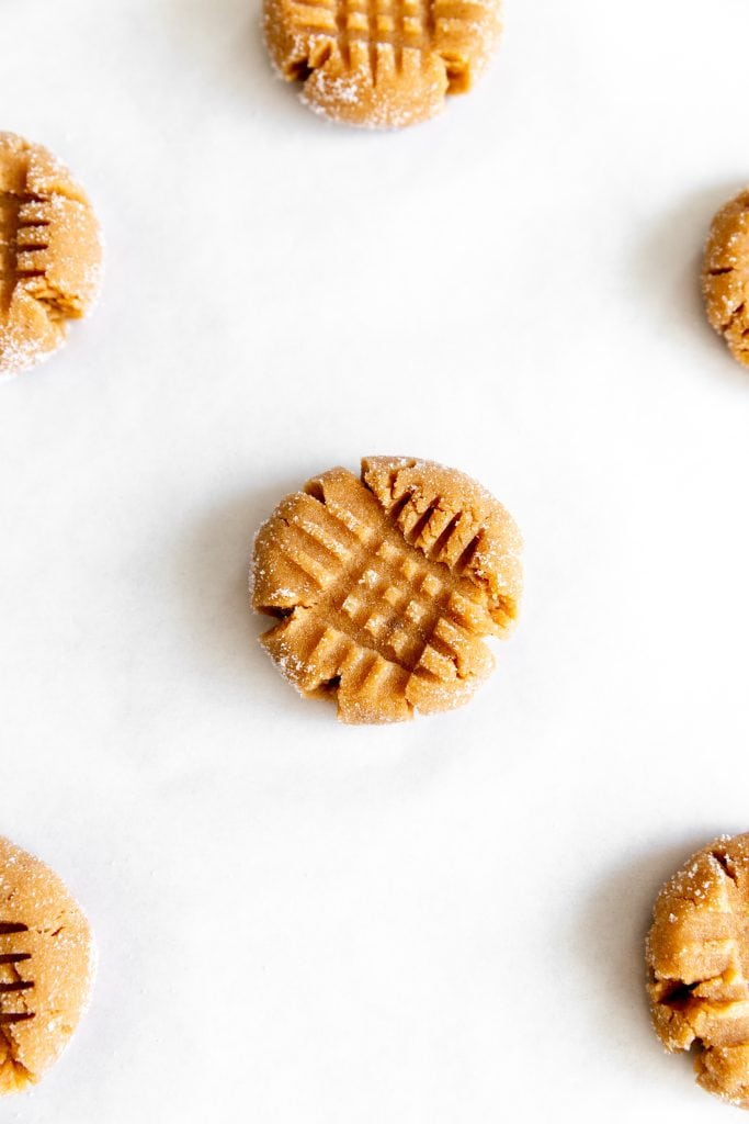 Single, unbaked peanut butter cookie on a baking sheet.