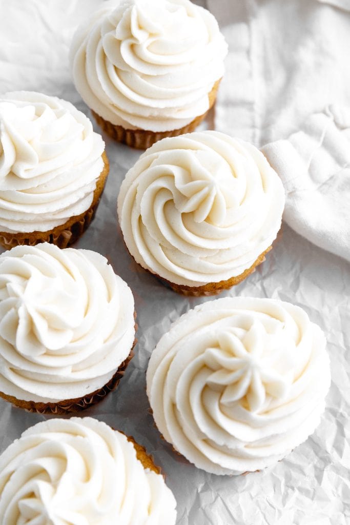 Tops of vanilla cupcakes piled with vanilla frosting.