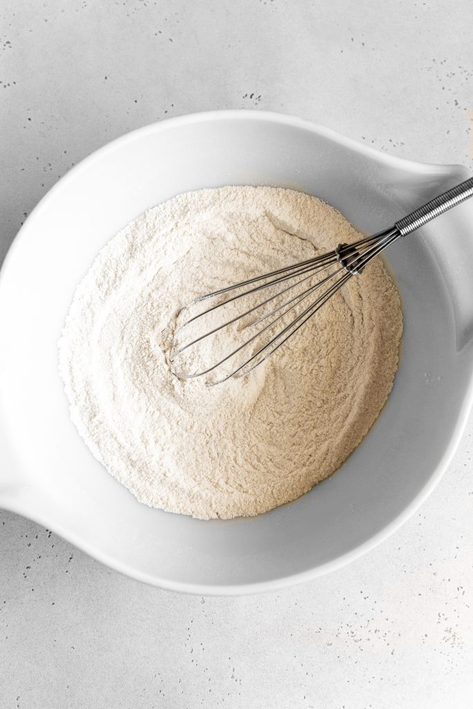 White bowl filled with flour and a whisk.