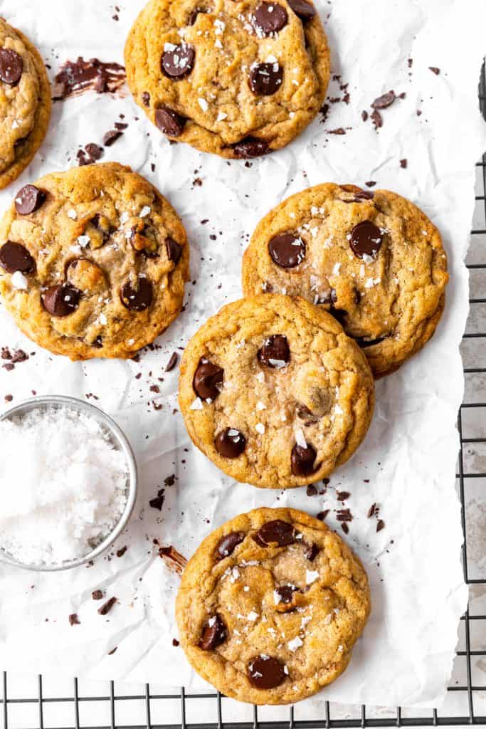 Banana chocolate chip cookies stacked on a white surface smeared with melted chocolate.