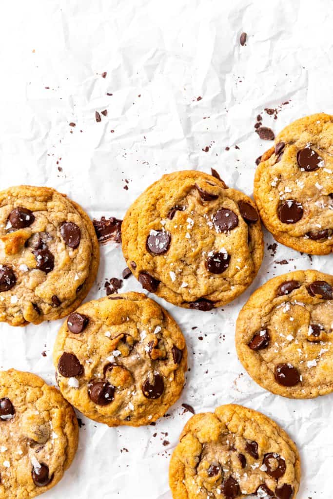 Vegan banana chocolate chip cookies on parchment smeared with chocolate.