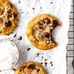 Banana chocolate chip cookie with a bite taken out of it and a cup of flaky salt.