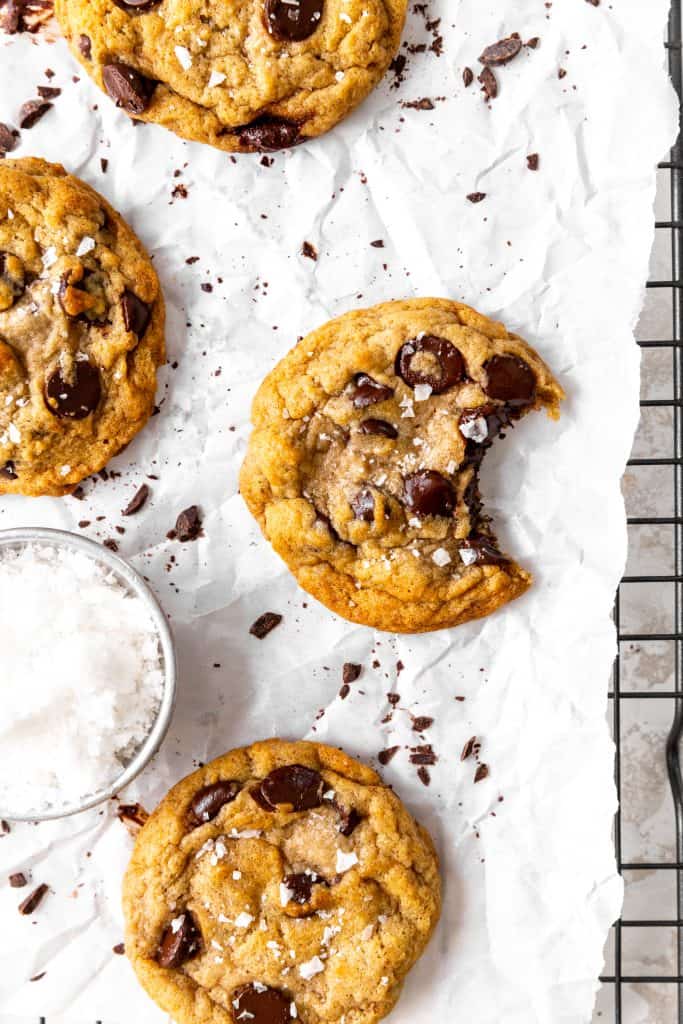 Banana chocolate chip cookie with a bite taken out of it and a cup of flaky salt.