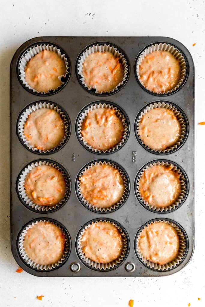 Unbaked vegan carrot cake cupcakes in a cupcake baking pan.